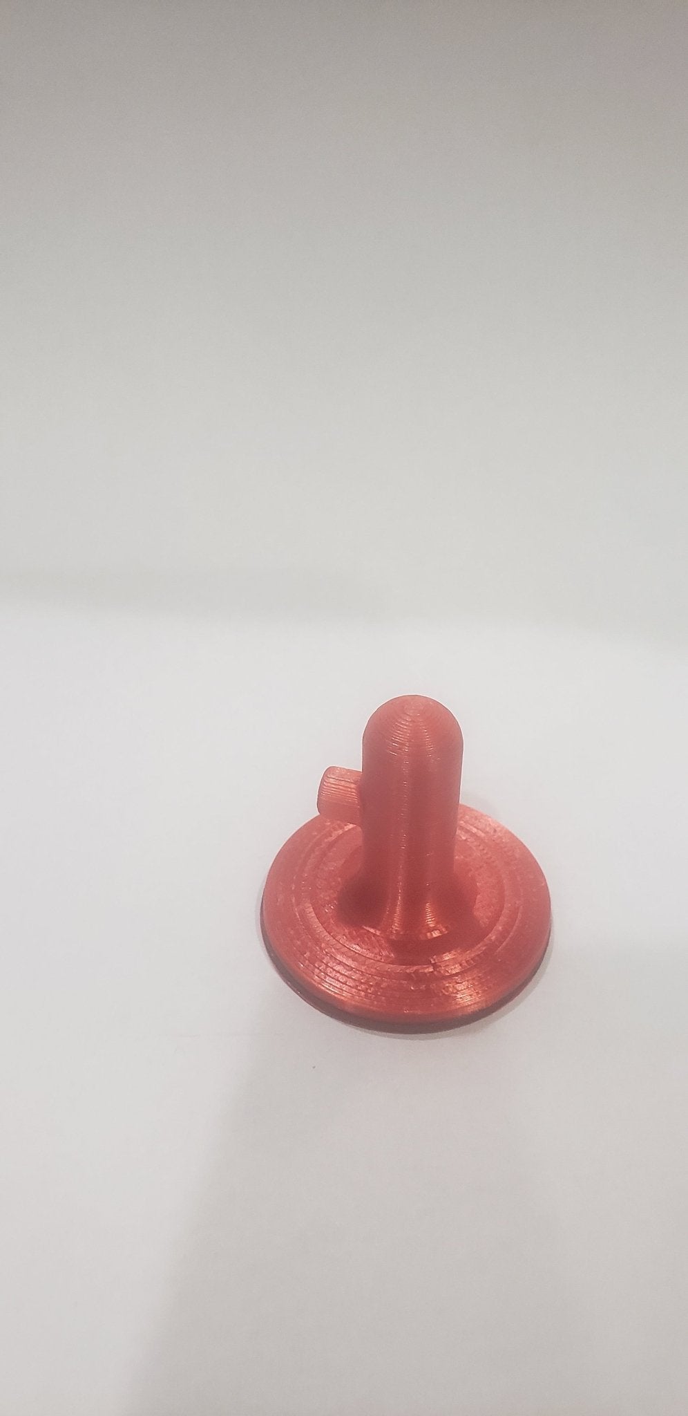 Red plastic component on a white background