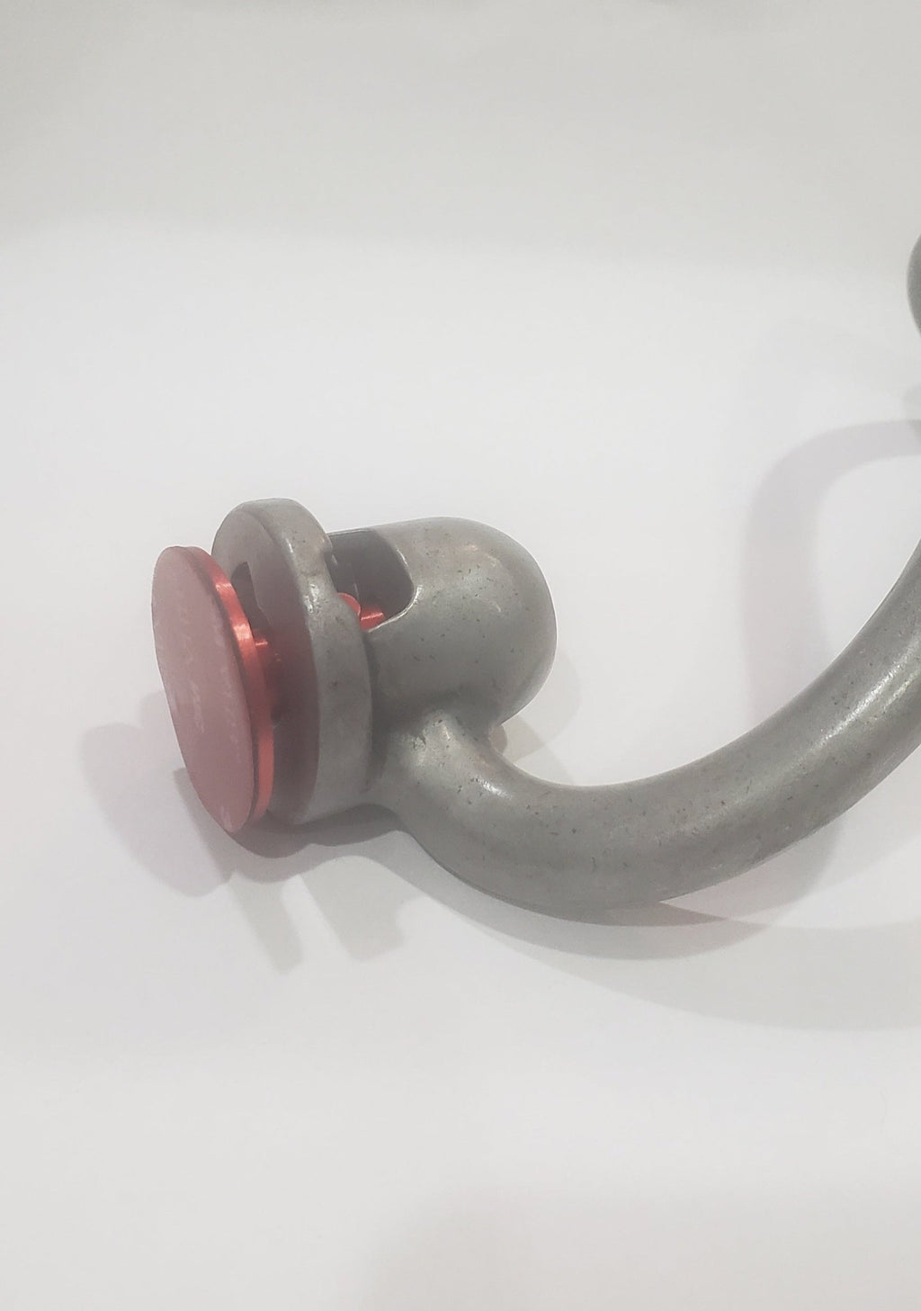 Gray metal object with a red circular component on a white background