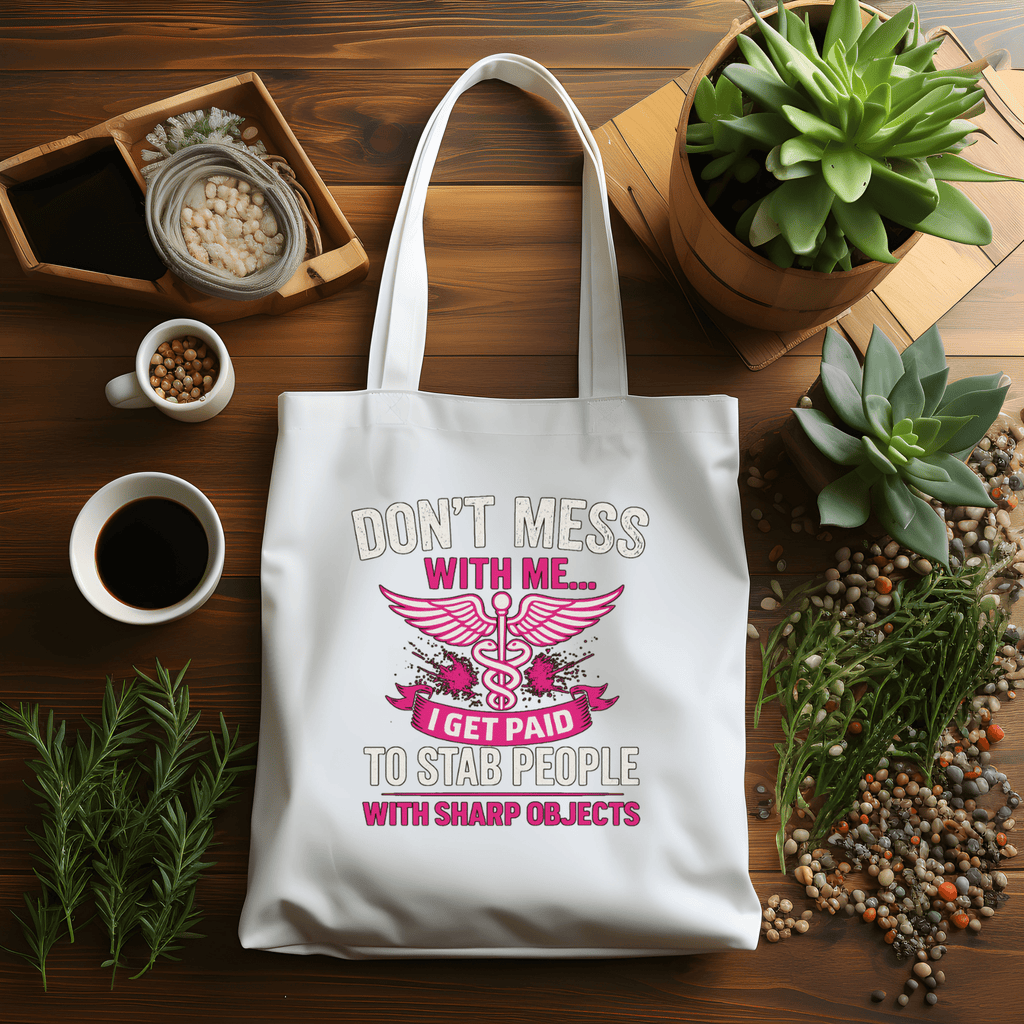 White tote bag with humorous design on a wooden table with plants and coffee.