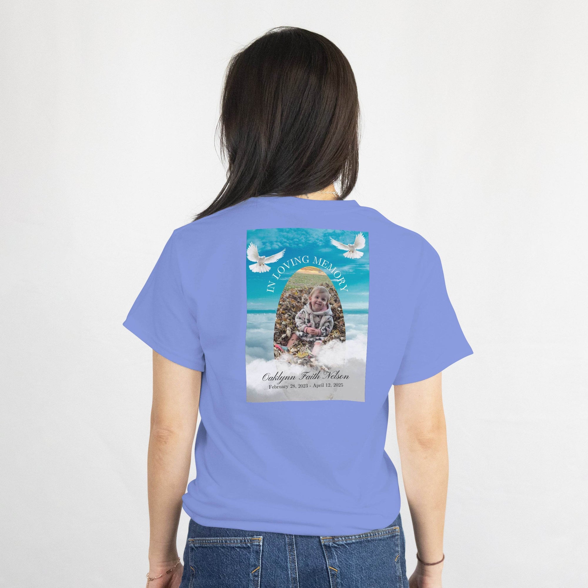Custom memorial T-shirt back with baby photo, name, and dates, plus doves in a serene sky design.