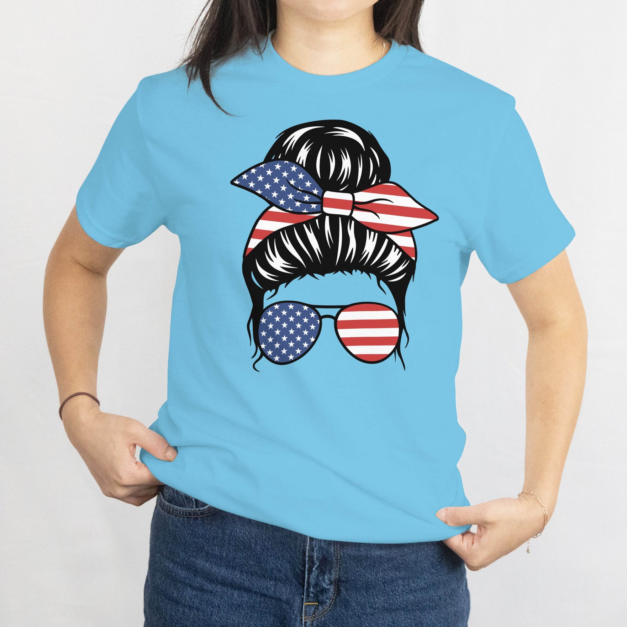 Gildan Patriotic Messy Bun T-Shirt graphic: bun with American flag bandana and matching flag sunglasses.