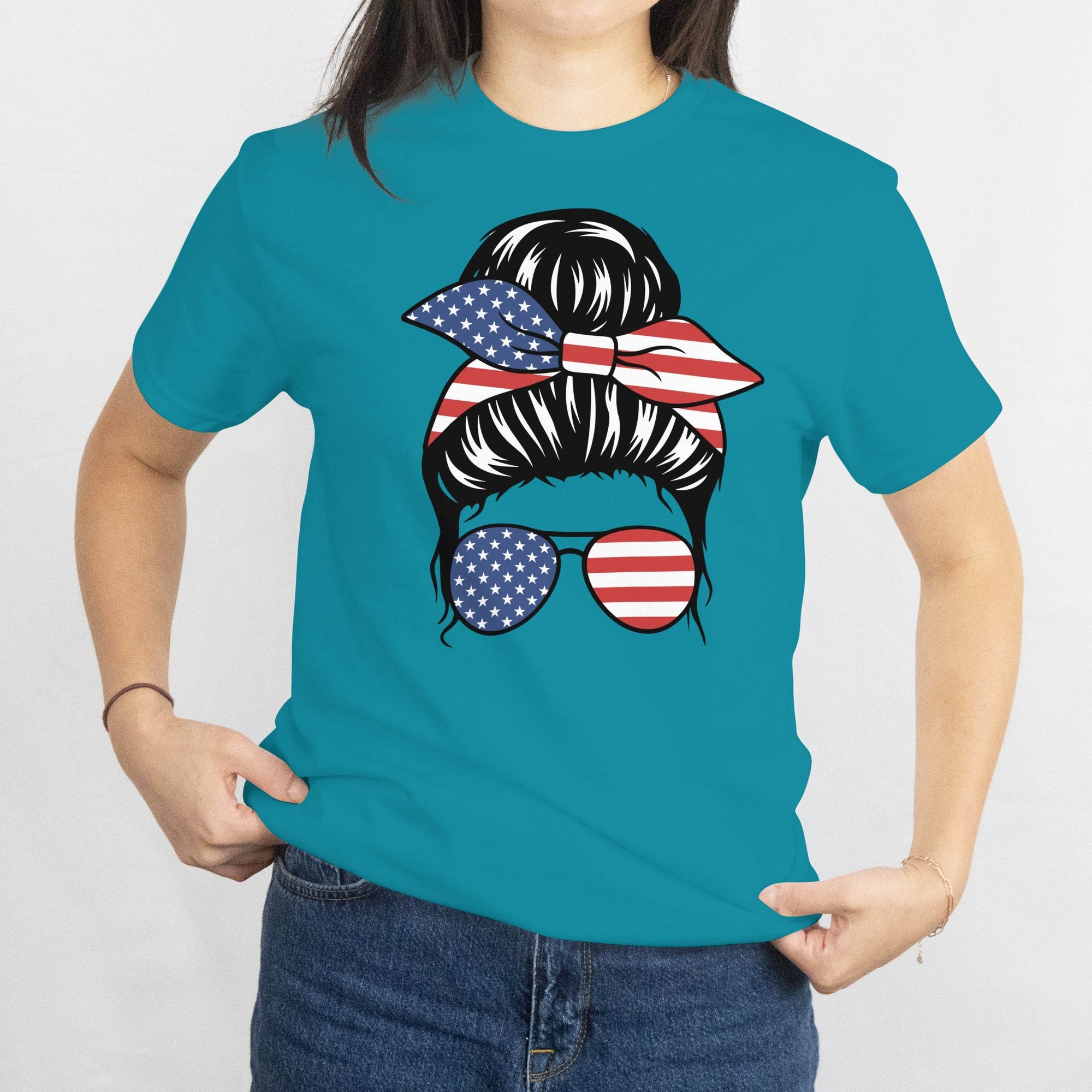 Gildan Patriotic Messy Bun T‑Shirt graphic: messy bun with star-spangled bandana and American flag sunglasses on teal tee.