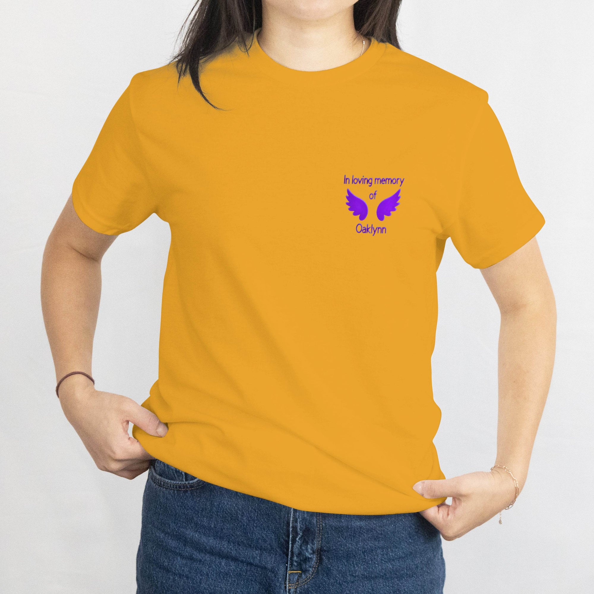 Mustard T-shirt with a small purple memorial design on the front reading In loving memory of Oaklynn with dove wings.