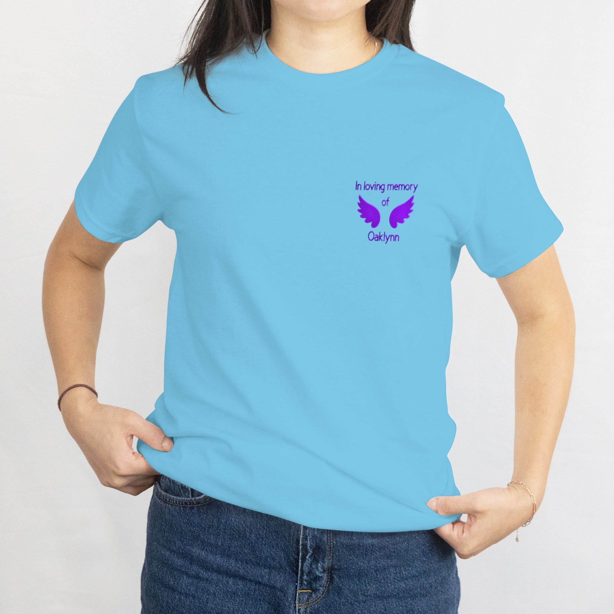 Light blue T-shirt with a purple memorial design on the left chest, 'In loving memory of Oaklynn' with wings.