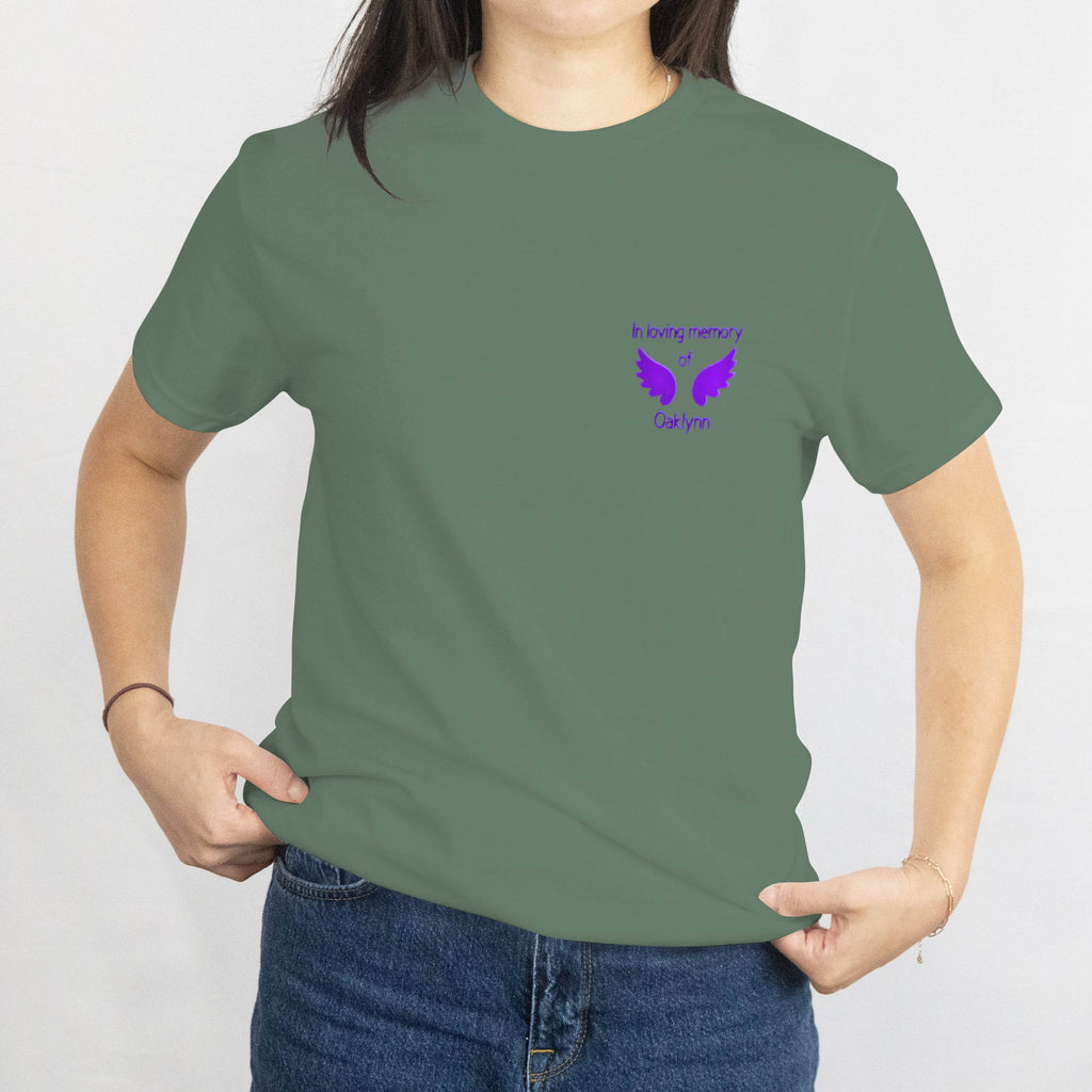 Olive-green memorial T-shirt with purple dove motif and 'In loving memory of Oaklynn' on the chest.