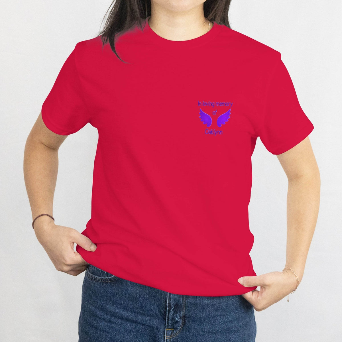 Red T-shirt with small blue wings memorial design on left chest reading In loving memory of Oaklynn.