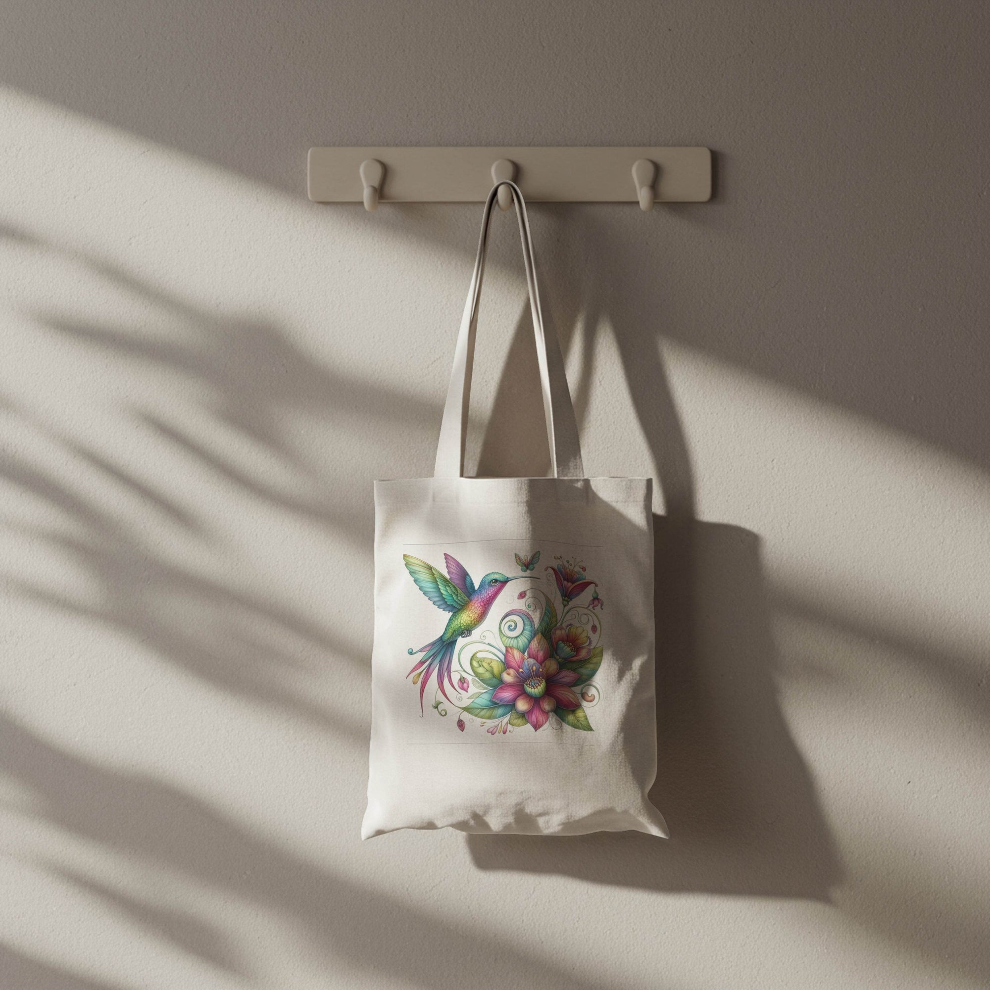 White tote bag featuring a vibrant butterfly and floral artwork, hanging on a wall.