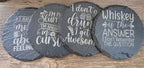Set of four round black slate coasters with white engraved quotes for a stylish home bar.