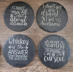 Four round black slate coasters with white chalk-style drink quotes.