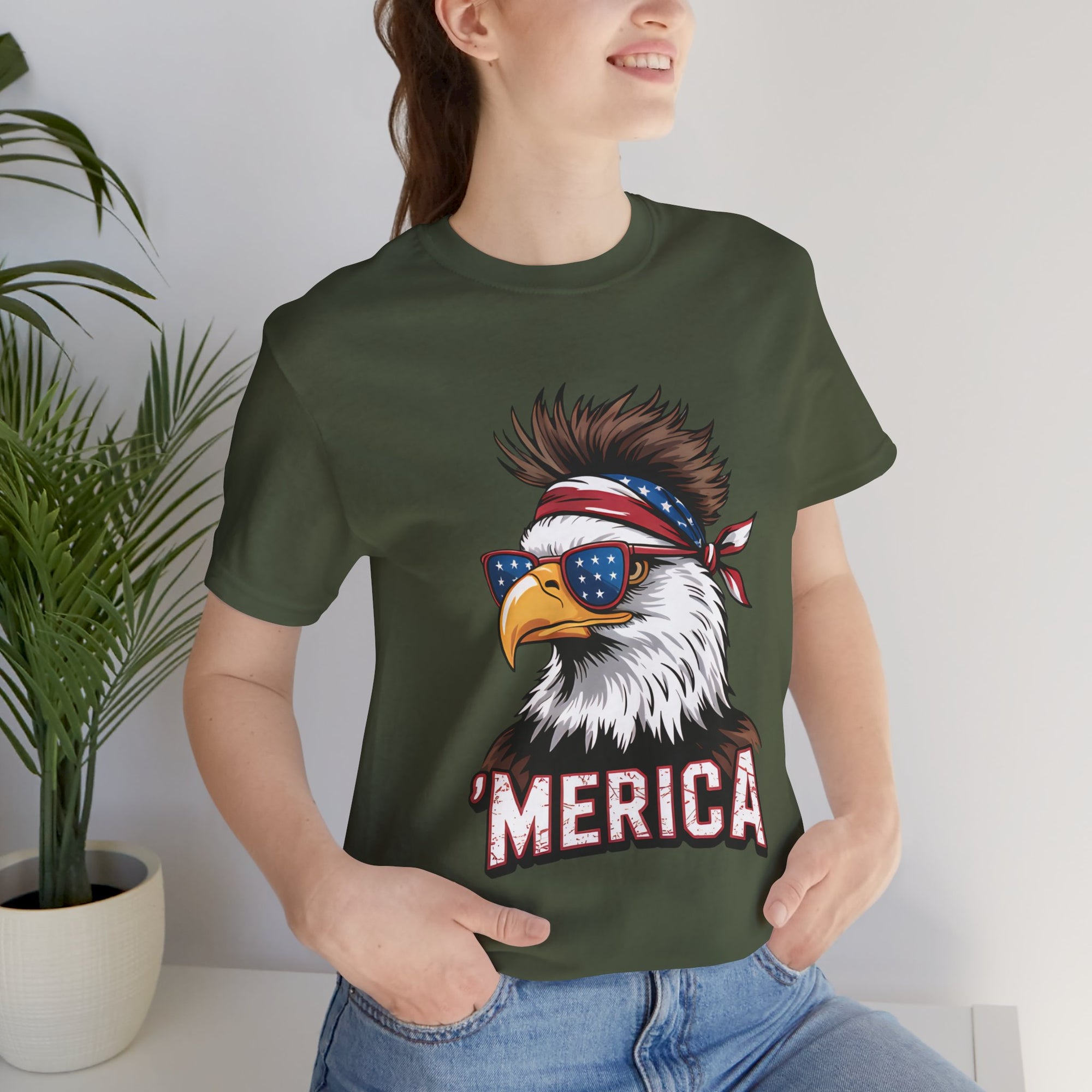 Green unisex tee with patriotic eagle graphic, star-spangled sunglasses and bandana, bold MERICA lettering.
