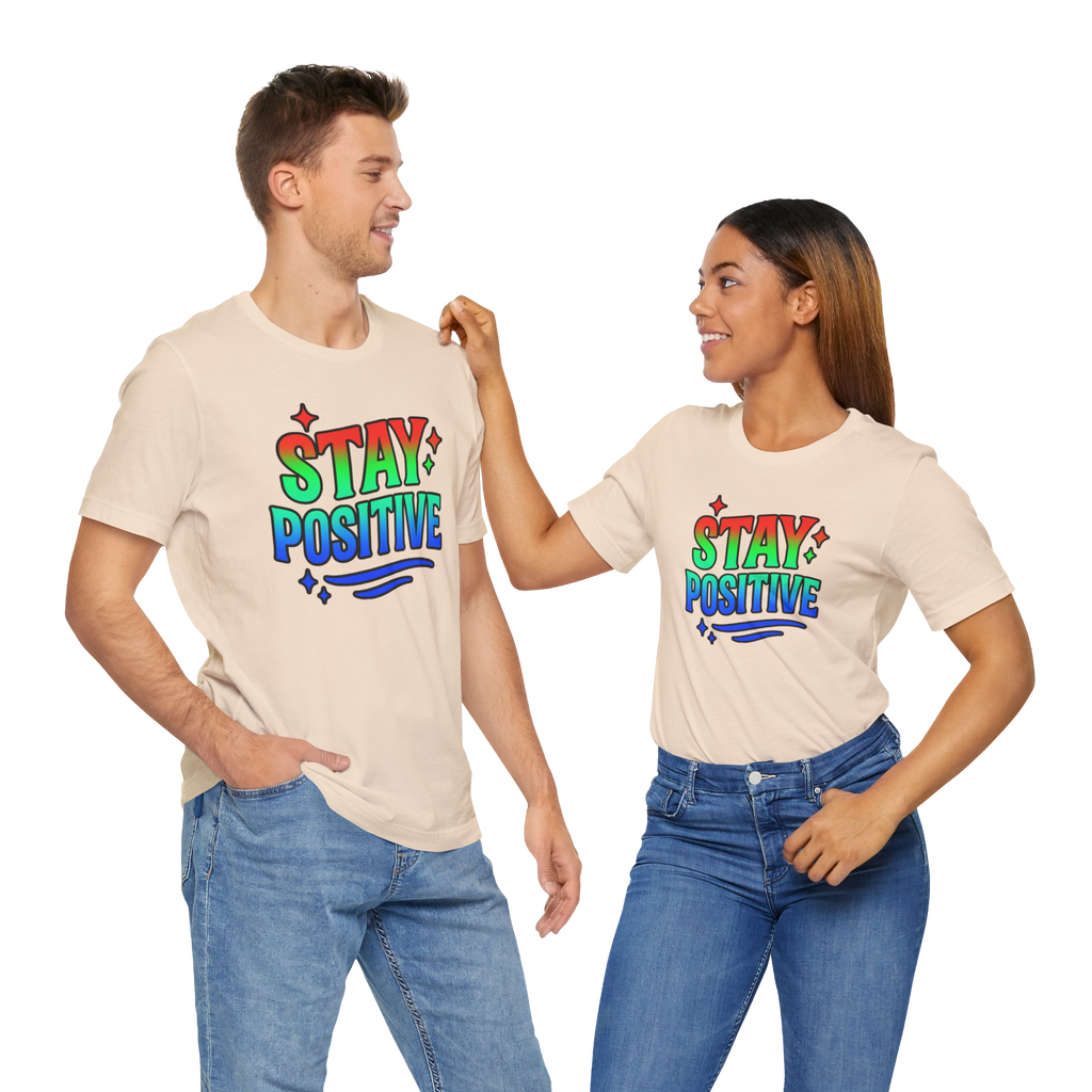 Two people wearing Stay Positive T-shirts with rainbow text design, smiling at each other.