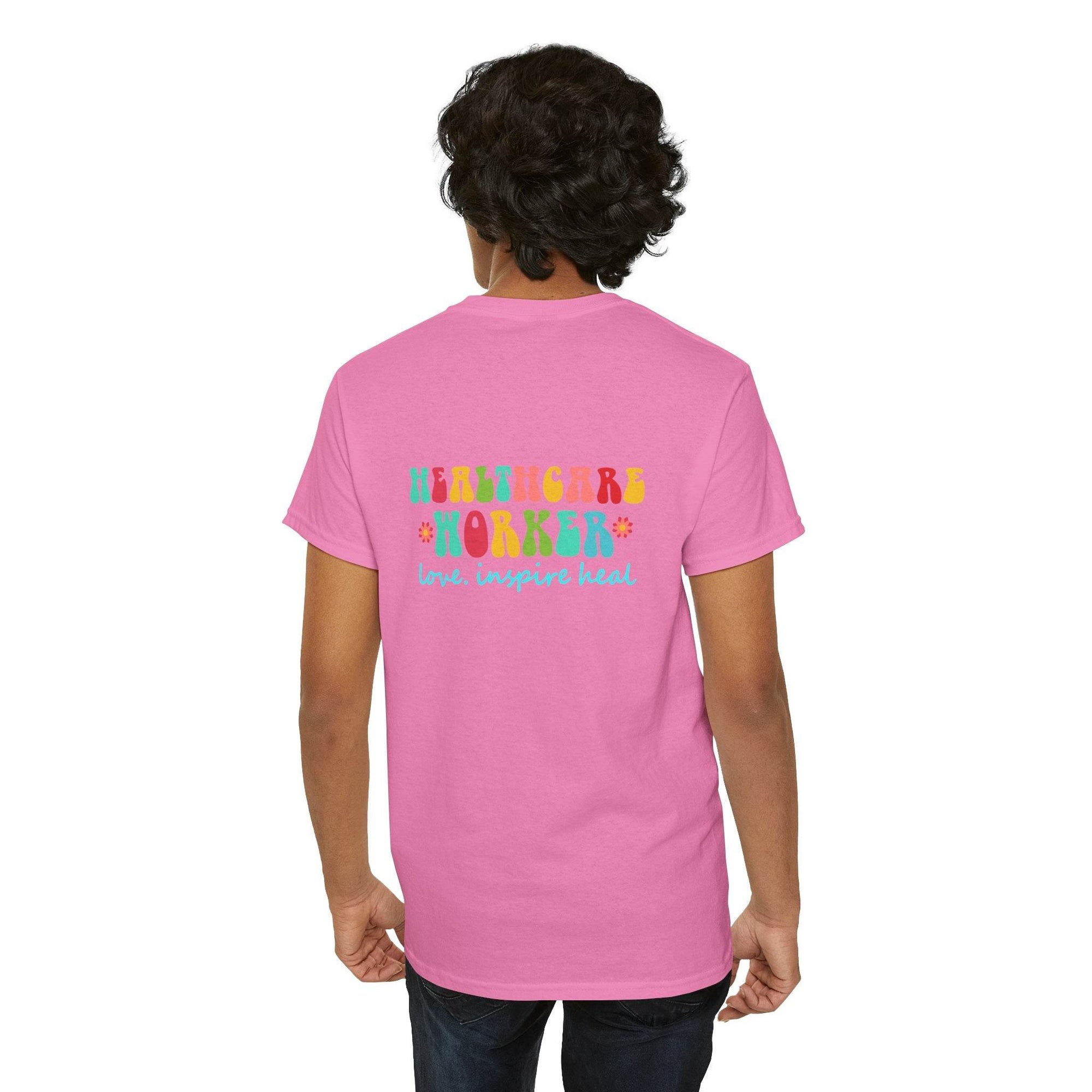 Pink healthcare workers t-shirt shown from back with rainbow HEALTHCARE WORKER and love inspire heal graphic.