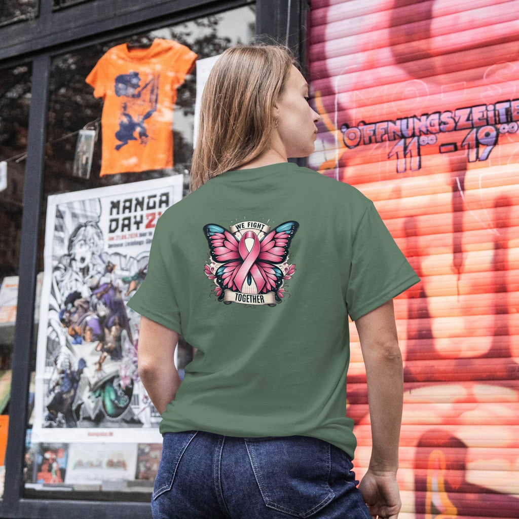 Person wearing a green t-shirt with a pink butterfly design and text, standing in front of a store window with posters and a colorful wall.