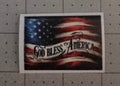 American flag with 'God Bless America' text on a gray pegboard background