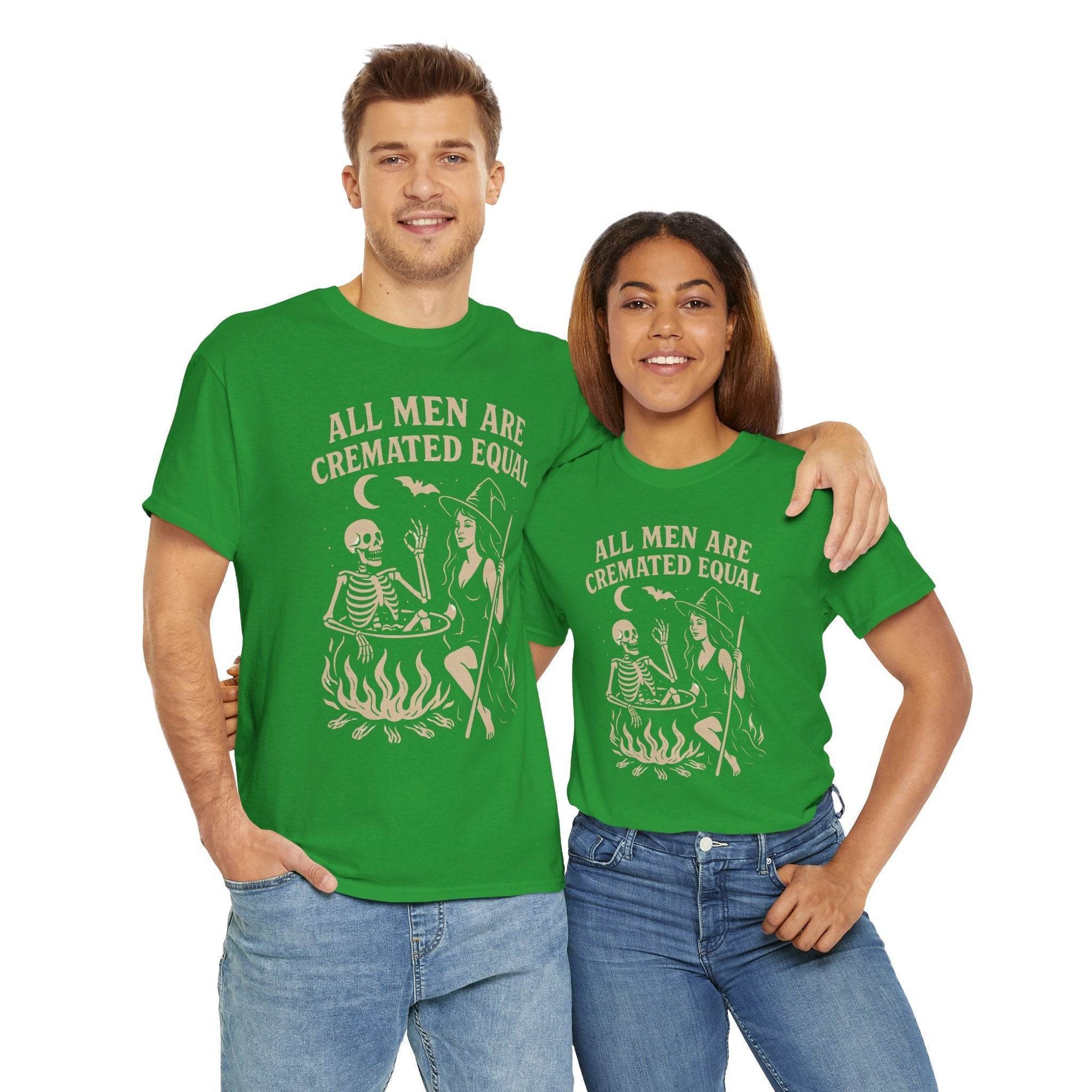Two people wear green All Men Are Cremated Equal witch cauldron Halloween tees, featuring a skeleton by a cauldron.