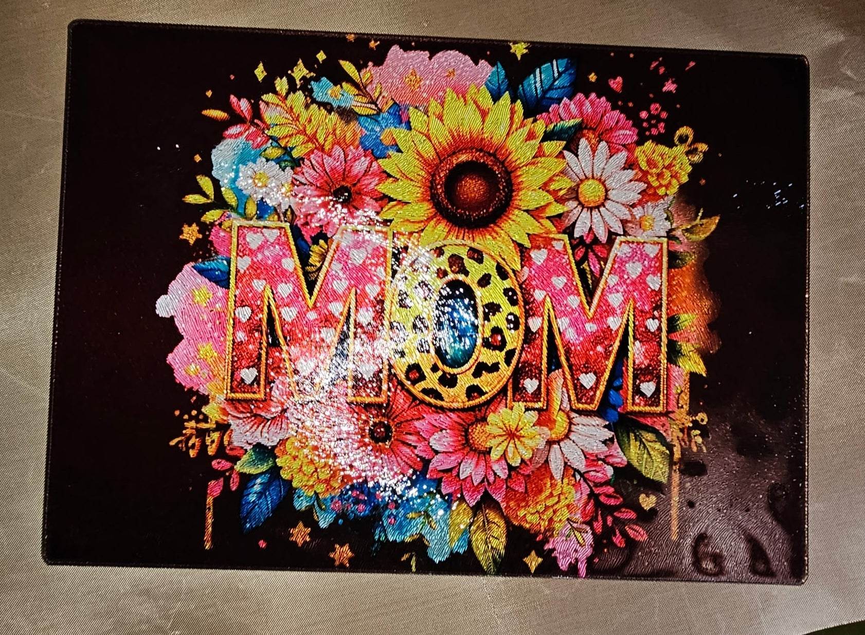 Bright multicolor floral MOM lettering with leopard center on a black background.