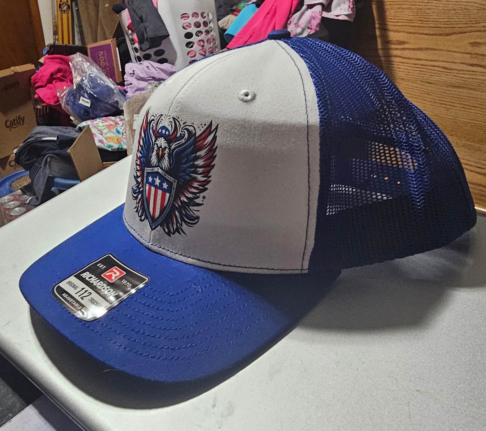 Custom Richardson 112 trucker hat with gray front, blue brim, navy mesh, colorful eagle holding a shield.